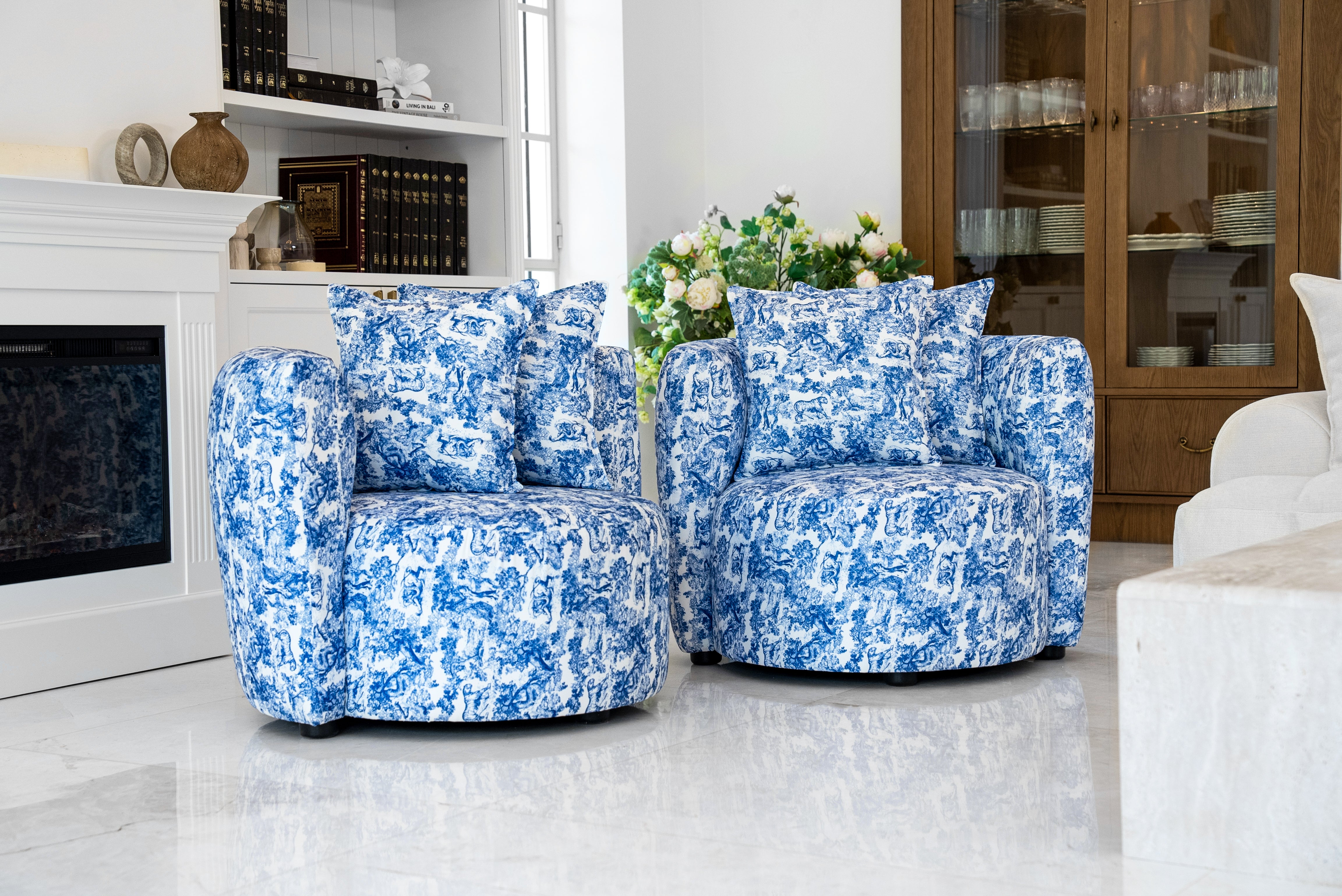 "Blue Towel armchair featuring a vibrant blue and white floral print upholstery. This barrel-style chair has a rounded back, plush seat cushion, and comes with two matching throw pillows, offering a striking accent piece for refined home decor."